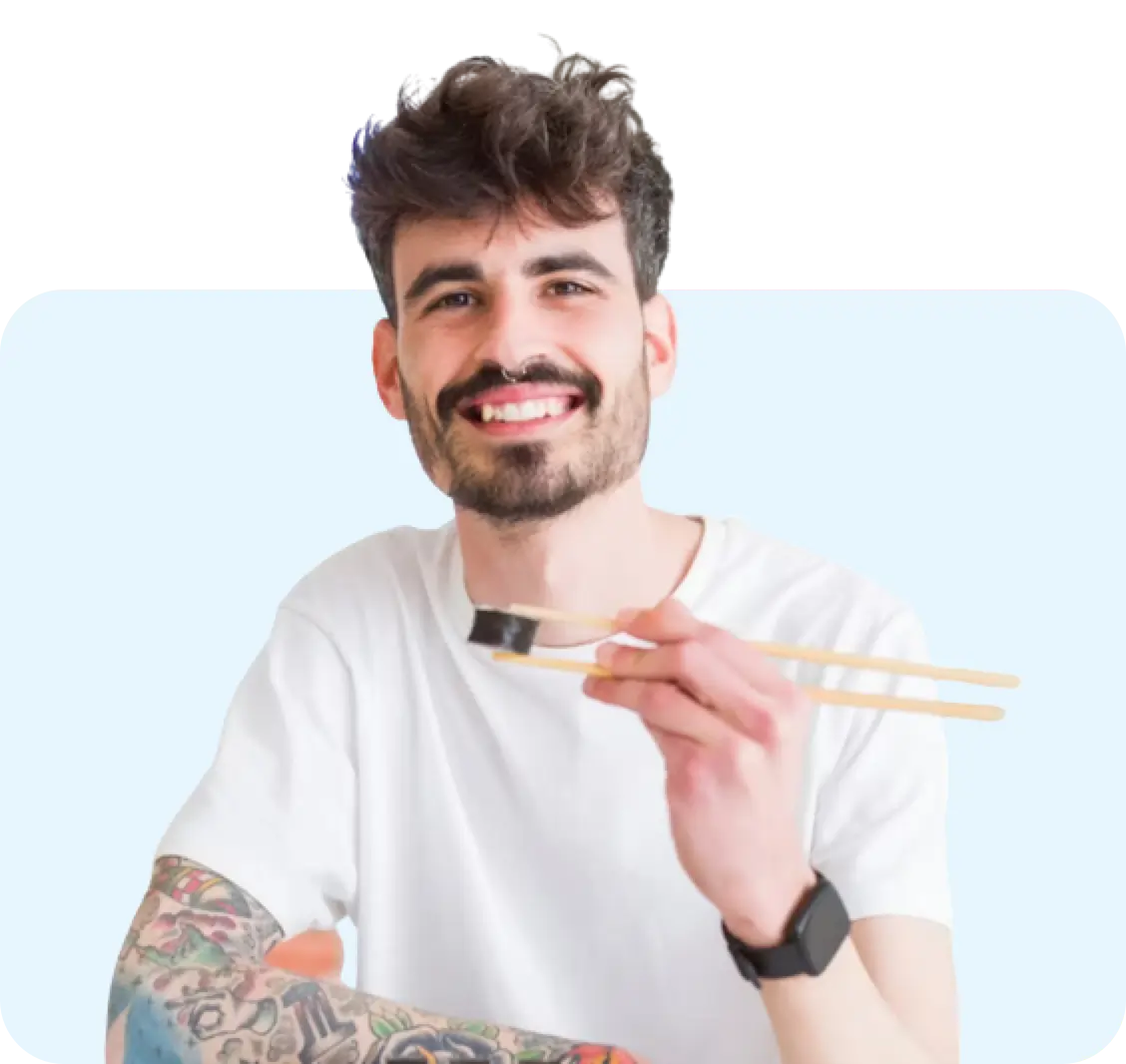 A man smiling and eating with chopsticks